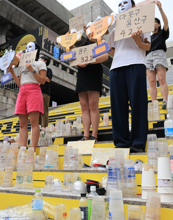 4일 서울 세종문화회관 앞에서 열린 서울시 구청 1회용품 사용 실태 결과발표 기자회견에서 서울환경연합 관계자들이 1회용컵 반입률이 가장 높았던 자치구에 불명예 트로피를 전달하는 퍼포먼스를 펼치고 있는 모습. 사진=연합뉴스